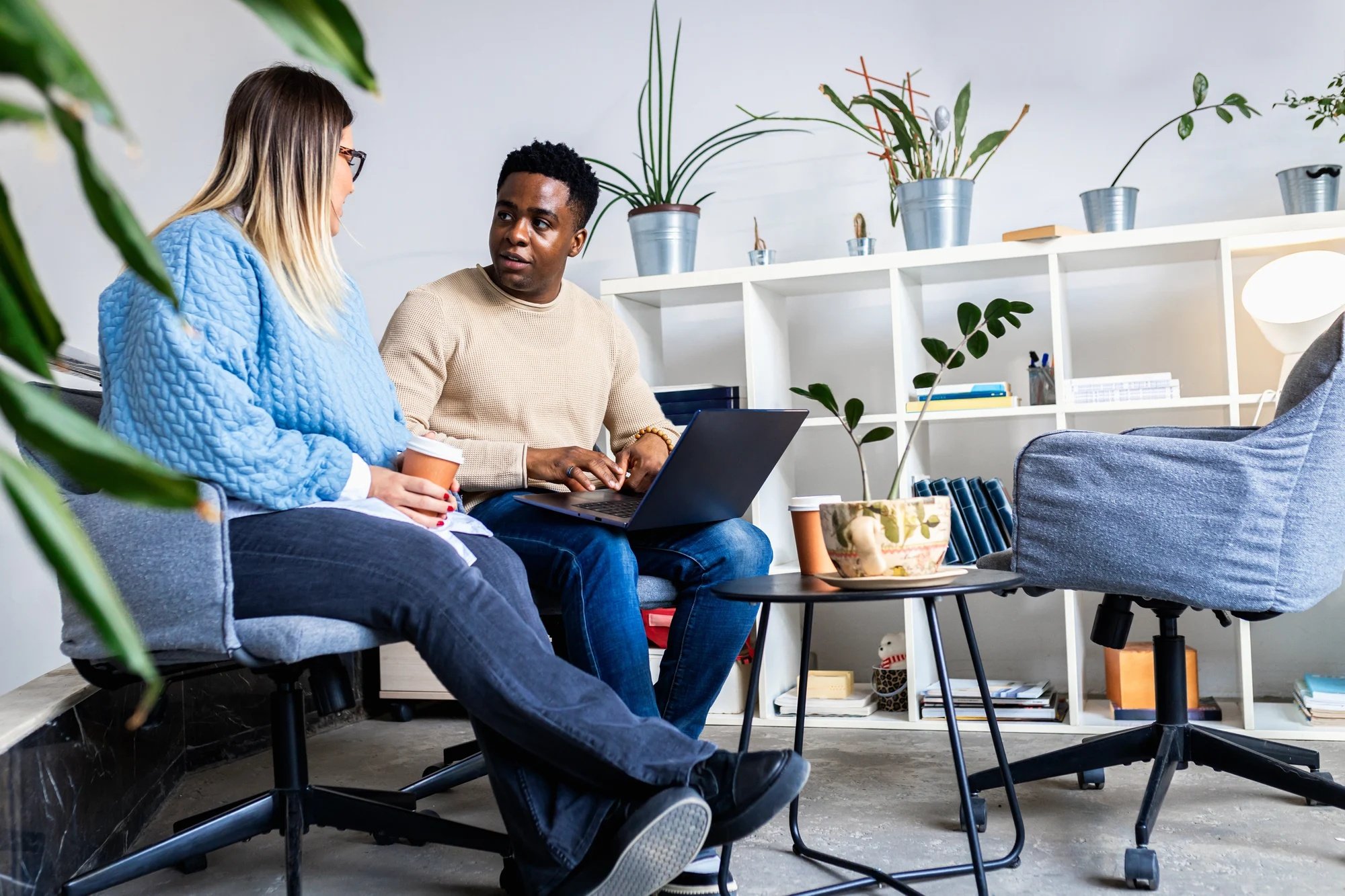 Dos personas sentadas compartiendo espacio de trabajo con un ordenador