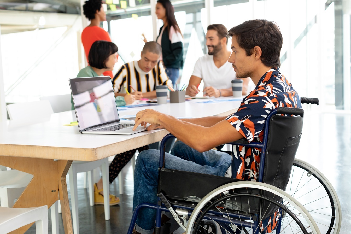 Hombre en silla de ruedas trabajando con un ordenador Hombre en silla de ruedas trabajando con un ordenador