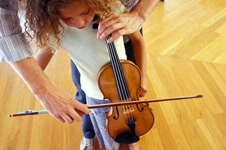 Padre enseñando a su hija a tocar el violín